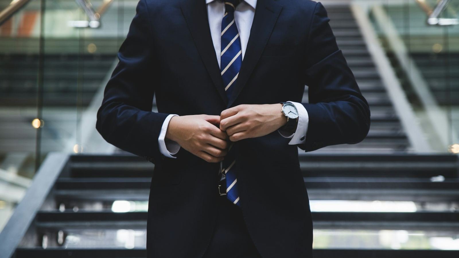 Professional in a navy suit fastening a jacket button